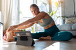© JOSEP SURIA/Westend61 - Woman exercising through digital tablet while stretching sitting on floor at home