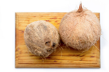 Whole coconuts on a wooden board on a white background. Tropical fruit from the Caribbean coasts