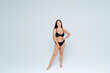 © OneInchPunch/Westend61 - Oversized young woman wearing black bikini posing against white background