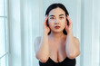 © OneInchPunch/Westend61 - Plus size model with hand in hair wearing black bra against white wall