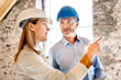 © peter scholl/Westend61 - Businesswoman wearing hardhat giving instruction to building contractor while working at construction site