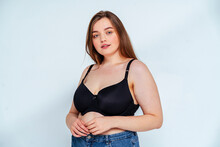 Curvy Fashion Model Wearing Bra And Jeans Standing Against White Background