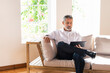 © steve brookland/Westend61 - Mature businessman using digital tablet while sitting with legs crossed at knee on sofa at home
