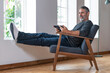 © steve brookland/Westend61 - Smiling businessman using digital tablet while sitting on armchair at home
