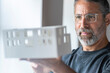 © steve brookland/Westend61 - Businessman wearing eyeglasses examining architectural model while standing at home