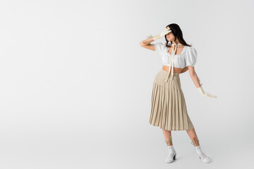 Sticker - young woman in stylish spring outfit and gloves with flowers posing on white