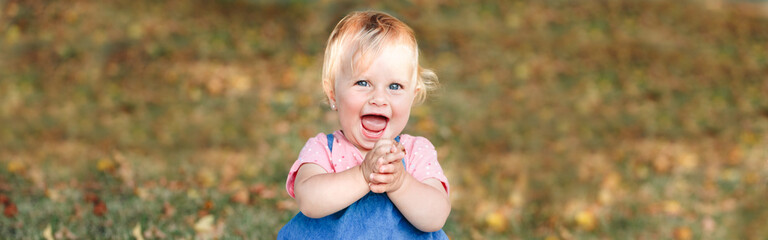 Cute smiling laughing baby girl in park outdoor. Adorable excited child toddler playing and having fun on summer day. Funny kid. Authentic lifestyle happy childhood. Web banner header.