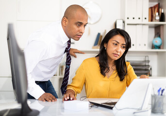 Focused male and female business colleagues looking at laptop screen, discussing new project in office