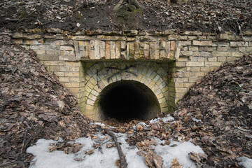 Wall Mural - entrance to a dark old abandoned brick tunnel in the woods in sunny day.