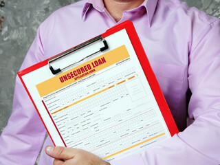 financial document in a hand with phrase UNSECURED LOAN Application Form. Horizontal shot. Close-up