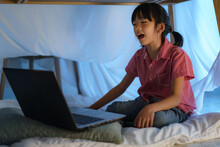 Asian Girl Child To Make A Camp To Play Imaginatively Watching A Film On Laptop In The Darkness Of The Camp In Living Room At Home.