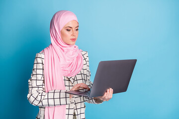 Wall Mural - Photo of young serious business woman send email read documents wear hijab isolated over blue color background