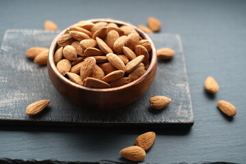 Wall Mural - Almonds nuts close-up in a  cup on a black shabby chic board on a black schiffer blurred background.Nuts and seeds. .Healthy fats.Heap Almonds shelled  nut closeup.Tasty organic snack 