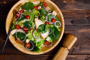 Top view angle photo of grilled chicken breast fresh and fillet vegetable salad with a variety of kinds of natural vegetables in wooden bowl on wood background. Healthy and diet menu idea.