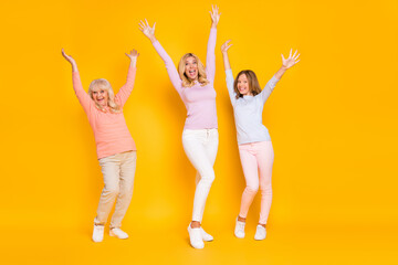 Poster - Full size photo of hooray three woman grand mom daughter hands up wear pastel cloth isolated on yellow background