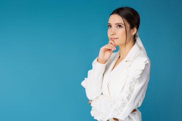 Pensive young businesswoman in classic office clothes on a blue background with empty side space for text or advertising.