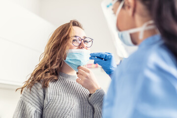 Smiling girl puts face mask off her nose so that a healthcare worker can take a sample for Covid-19 testing