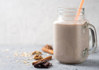 Wall Mural - Glass jar of milkshake smoothie with chocolate, coffee, oatmeal and nuts copy space