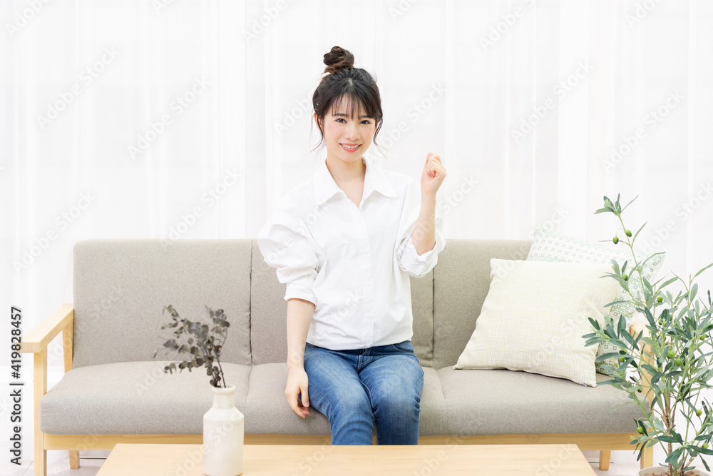 窓際のソファに座ってガッツポーズをする若い女性 Wall Mural Garage38 窓際のソファに座ってガッツポーズをする若い女性 Wall Mural Garage38