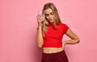 © kiuikson - Young woman in sport suit touching her temple with a glass of water isolated on pastel background