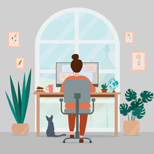 Woman working at home on computer. Cozy creative workplace homeoffice with plants, paintings and cat. Freelance concept.