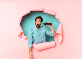 Wall Mural - young crazy bearded man. shocked or surprised expression. binoculars concept