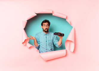 Wall Mural - young crazy bearded man confused expression. binoculars concept