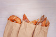 Assortment of puff pastries in paper ecological bags on a white wooden background