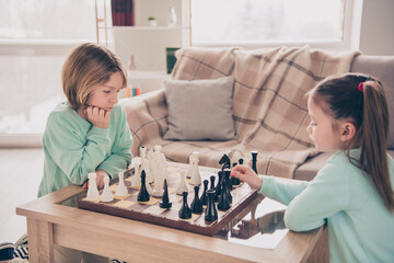 Portrait of two concentrated thoughtful school persons playing chess hand touch figure free time home indoors