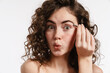 Half-naked surprised woman plucking her eyebrows with tweezer