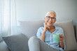 © Dragana Gordic - Shot of a senior woman enjoying a relaxing coffee break on the sofa at home. Portrait of smiling senior woman drinking coffee at home while looking at camera.