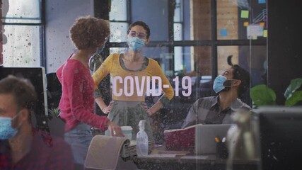 Poster - Covid-19 text against office colleagues wearing face mask laughing together at office