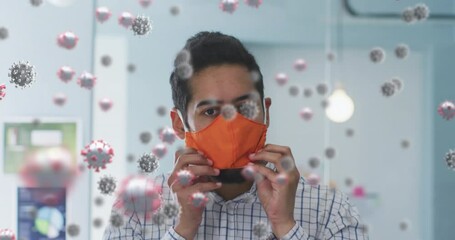 Wall Mural - Multiple covid-19 cells floating against man adjusting his face mask at office