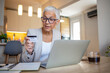 © Dragana Gordic - Mature woman using credit card making online payment at home. Successful old woman doing online shopping using laptop.