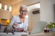 © Dragana Gordic - Mature Woman Holding Credit Card and Using Laptop Computer While Paying Bills at Home With Credit Card. E-banking Concept. Woman paying bills from home