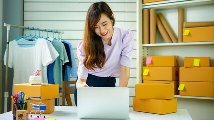 Startup small business SME, Entrepreneur owner smiling and checking sales on the computer screen after she succeeded in thinking differently in the online sme business.