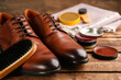 Shoe care products and footwear on wooden table, closeup
