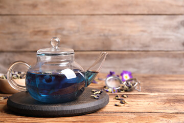 Organic blue Anchan in glass pot on wooden table, space for text. Herbal tea