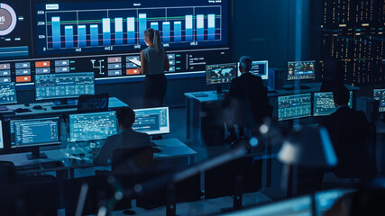 Poster - Software Engineers Working in a Room with a Big Screen in a Modern Monitoring Office with Live Analysis Feed with Charts. Monitoring Room Big Data Scientists and Managers Sit in Front of Computers.