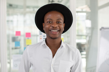 Close up portrait of cheerful handsome young african man standing at office in front of glass wall with stickers