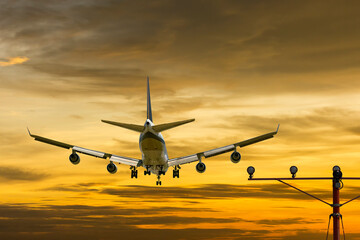 Wall Mural - rear view airplanes for commercial passenger or cargo transportation aircraft flying and spread the wheel for landings to airport on golden sunset sky in dusk or evening