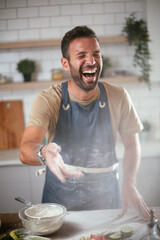 Wall Mural - Young man preparing bread at home. Happy man having fun while baking a fresh pasta..