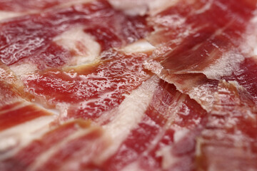 Macrophotography of slices of Iberian ham cut by hand, the natural fat oozes between the veins, impregnating all the cured meat,