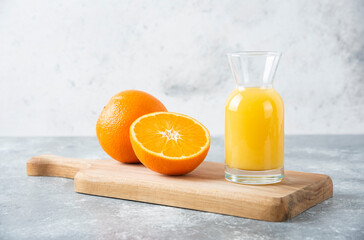 Wall Mural - Glass pitcher of juice with sliced orange fruit on a wooden board