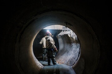 Wall Mural - Sewer tunnel worker examines sewer system damage and wastewater leakage