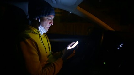 Poster - A man uses a mobile phone in a night car. He looks at the phone screen, clicks on the screen. Getting information on the way.