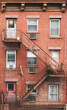 Old brick tenement house with fire escape, New York City, USA.