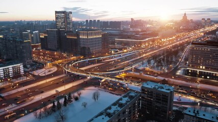 Wall Mural - View from above to Moscow multi-level highway in winter lit by the sunset light. Camera showing panorama of the evining city and then coming closer to the junction with a lot of traffic.