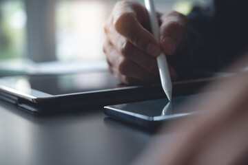 Close up of man hand using touchscreen pen on digital tablet and mobile smartphone, e-signing, electronic signature