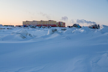 Wall Mural - Winter arctic landscape.  View of a small arctic village on the shores of the frozen sea. Multi-colored residential buildings. Cold weather. Harsh polar climate. Tavayvaam, Chukotka, Siberia, Russia.